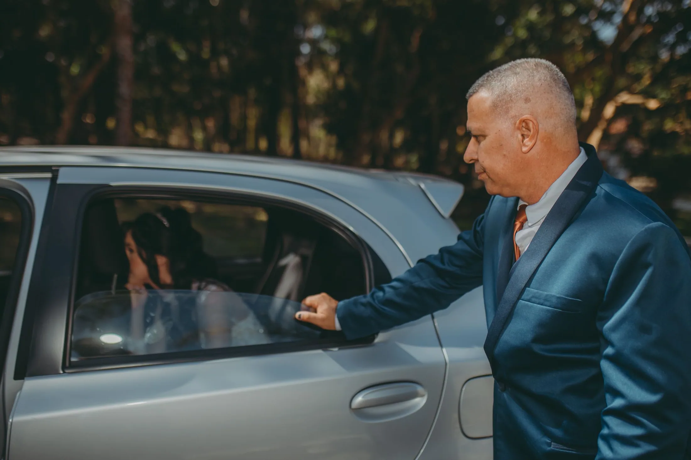 A formal wedding arrival beside a silver car